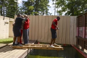 Players from the University of Louisiana at Lafayette's football team use teamwork and problem solving skills to escape from a prisoner of war camp during a leadership and teamwork exercise at the Louisiana National Guard’s leadership reaction course at Camp Beauregard in Pineville, La., July 8, 2016. The senior football players’ leadership, teamwork and problem solving skills were tested through different scenarios at the LRC. (U.S. Army National Guard photo by Sgt. Noshoba Davis, Louisiana National Guard Public Affairs Representative)