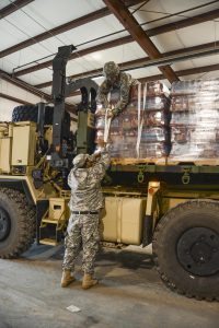 Members of the Louisiana National Guard's 1086th Transportation Company, and Pfc. Mason Madrigal, a Bunkie, Louisiana native, secure pallets of bottled water on a palletized load system vehicle to be delivered to the town of St. Joseph, Jan. 5, 2017. The LANG received the mission to deliver water after Governor John Bel Edwards declared a public health emergency due to elevated levels of lead and copper in the water. (U.S. Army National Guard photo by Sgt. Noshoba Davis)