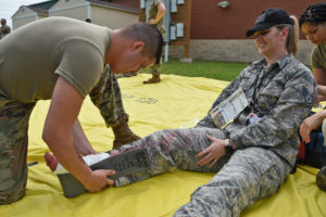Staff Sgt. Donavan Snowden, 159th Medical Group medic, treats a simulated foot injury on Staff. Sgt Angelique Romero, Louisiana Air National Guard Headquarters, during a mass causality exercise at the Air Dominance Center in Savannah, Ga., June 9, 2021. This exercise is part of the 2021 annual training for the 159th Fighter Wing to ensure mission readiness and trust between its Airmen to protect what matters. (U.S. Air National Guard photo by Staff Sgt. Ryan Sonnier)   