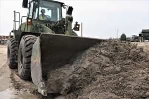 Spc. Josie Perkins from Bastrop, Louisiana, with the 1023rd Vertical Engineer Construction Company, 225th Engineer Brigade, removes sand from a roadway with a Five-Yard Loader in Grand Isle, Louisiana, during post Hurricane Ida reconstruction, Sept. 6, 2021. (US Army National Guard photo by Staff Sgt. Gregory Stevens)